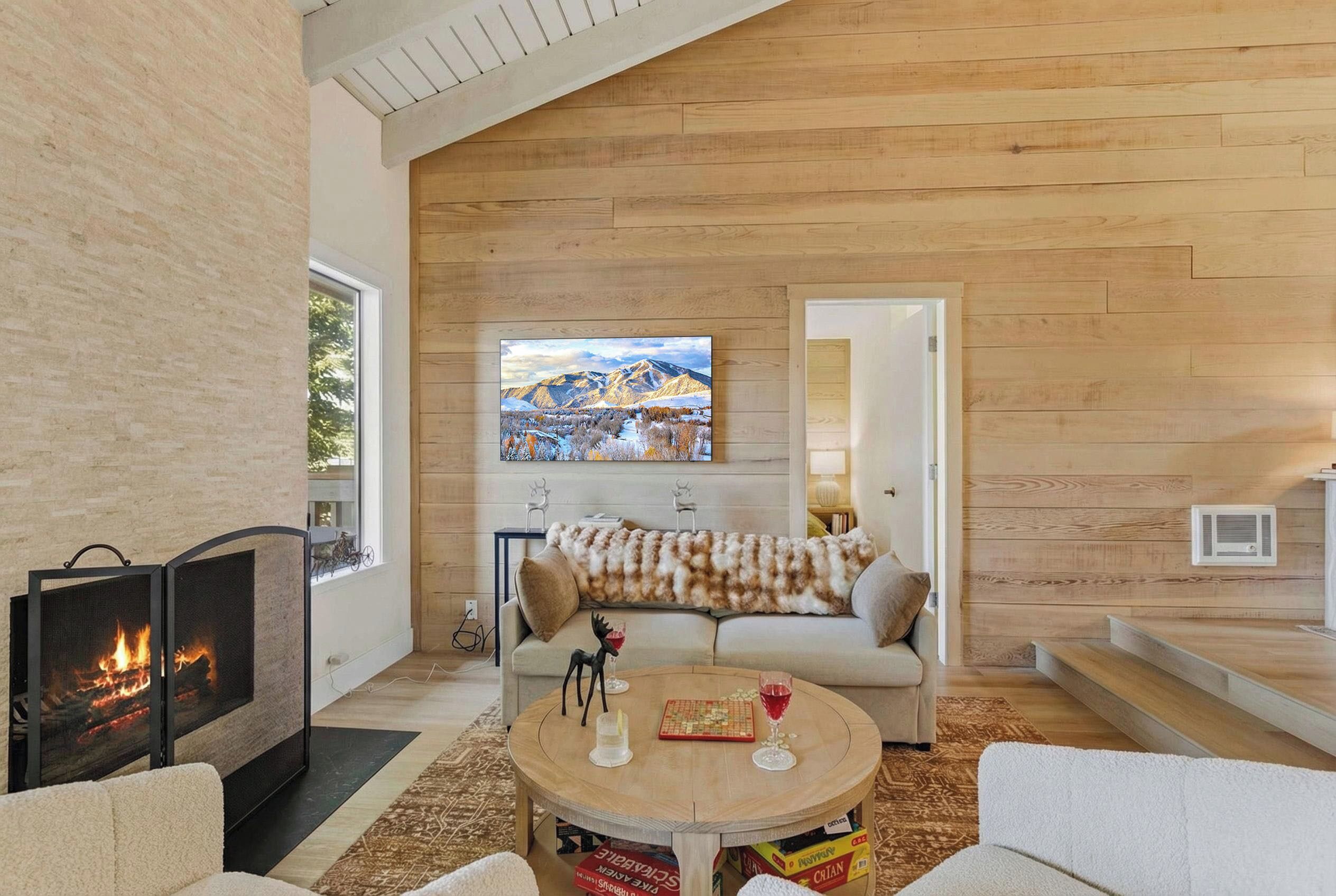 A modern living room with a fireplace, a sofa, a coffee table, and a painting on the wall.