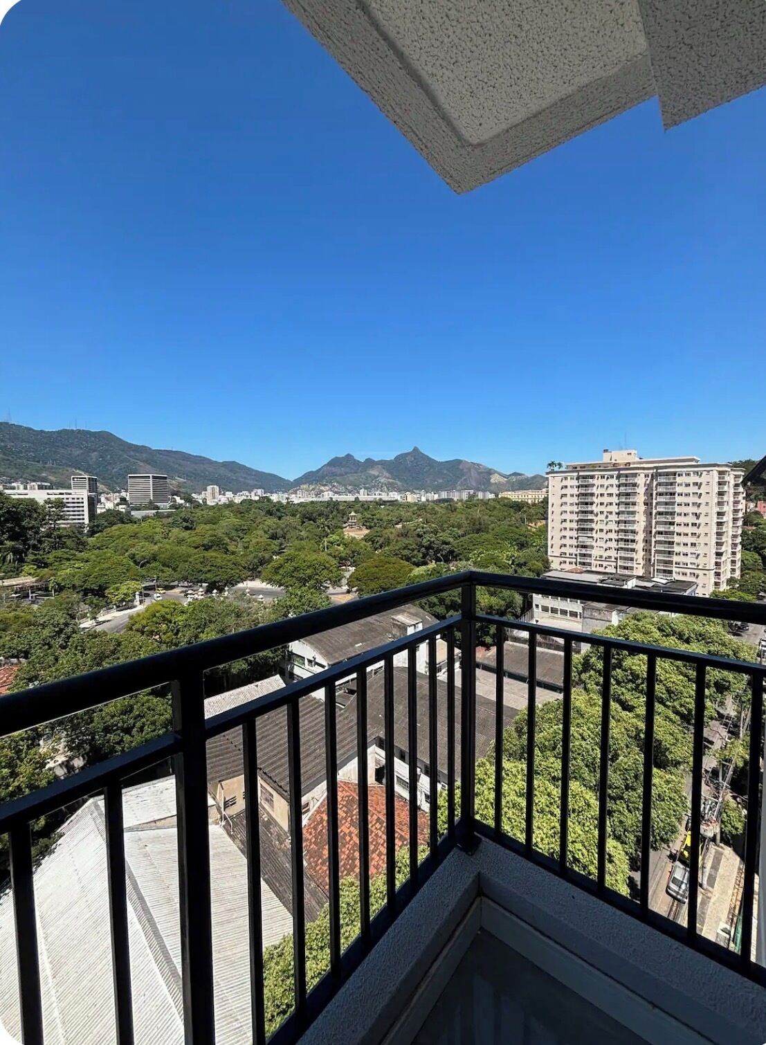 A balcony with a view of a cityscape, including buildings and mountains.
