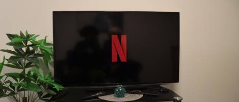 A flat-screen TV on a black stand with a decorative anchor above it.