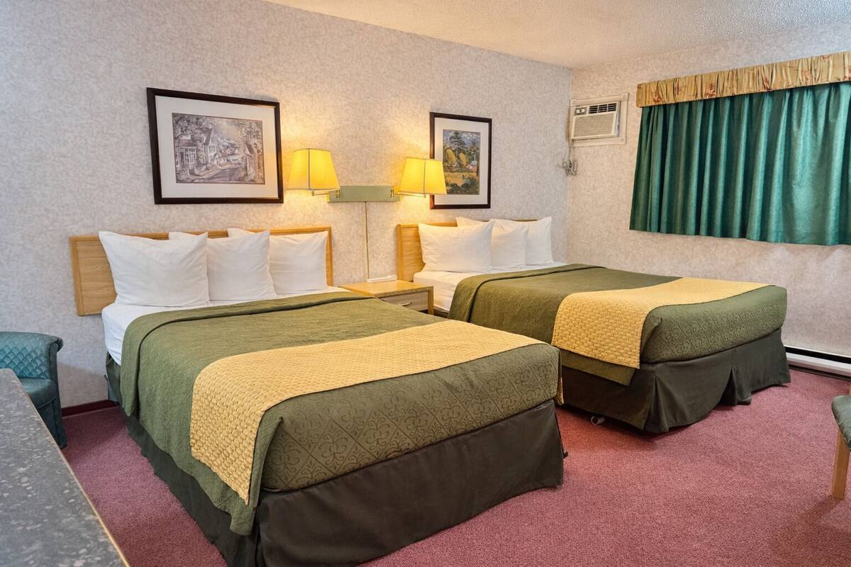 Une chambre d’hôtel avec deux lits, un bureau, une chaise et deux lampes.