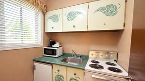 A compact kitchen with a microwave, stove, and sink. - Rychter Hotel Hope (Hope)