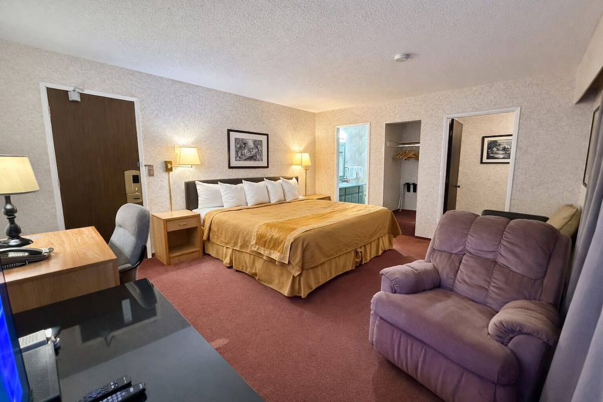 Une chambre d’hôtel comprenant un lit, des tables de chevet, un bureau, une chaise et un téléviseur.