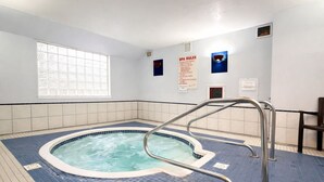 Un bassin de spa doté d’un sol carrelé, d’une échelle en métal et d’une fenêtre ornée de vitraux.