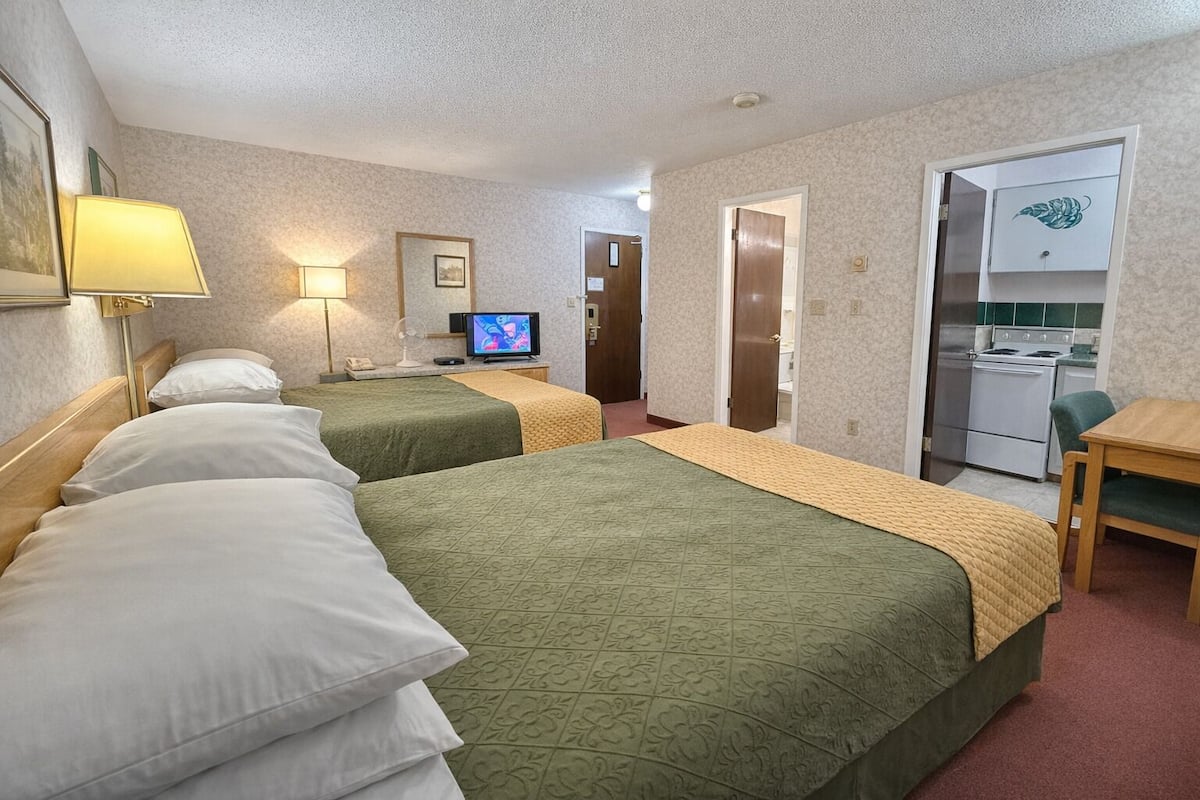 Une chambre d’hôtel avec deux lits, une télévision, un bureau et une kitchenette.
