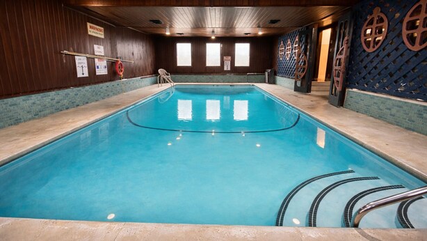 Une piscine intérieure avec des murs en bois, un sol carrelé et une eau bleue.
