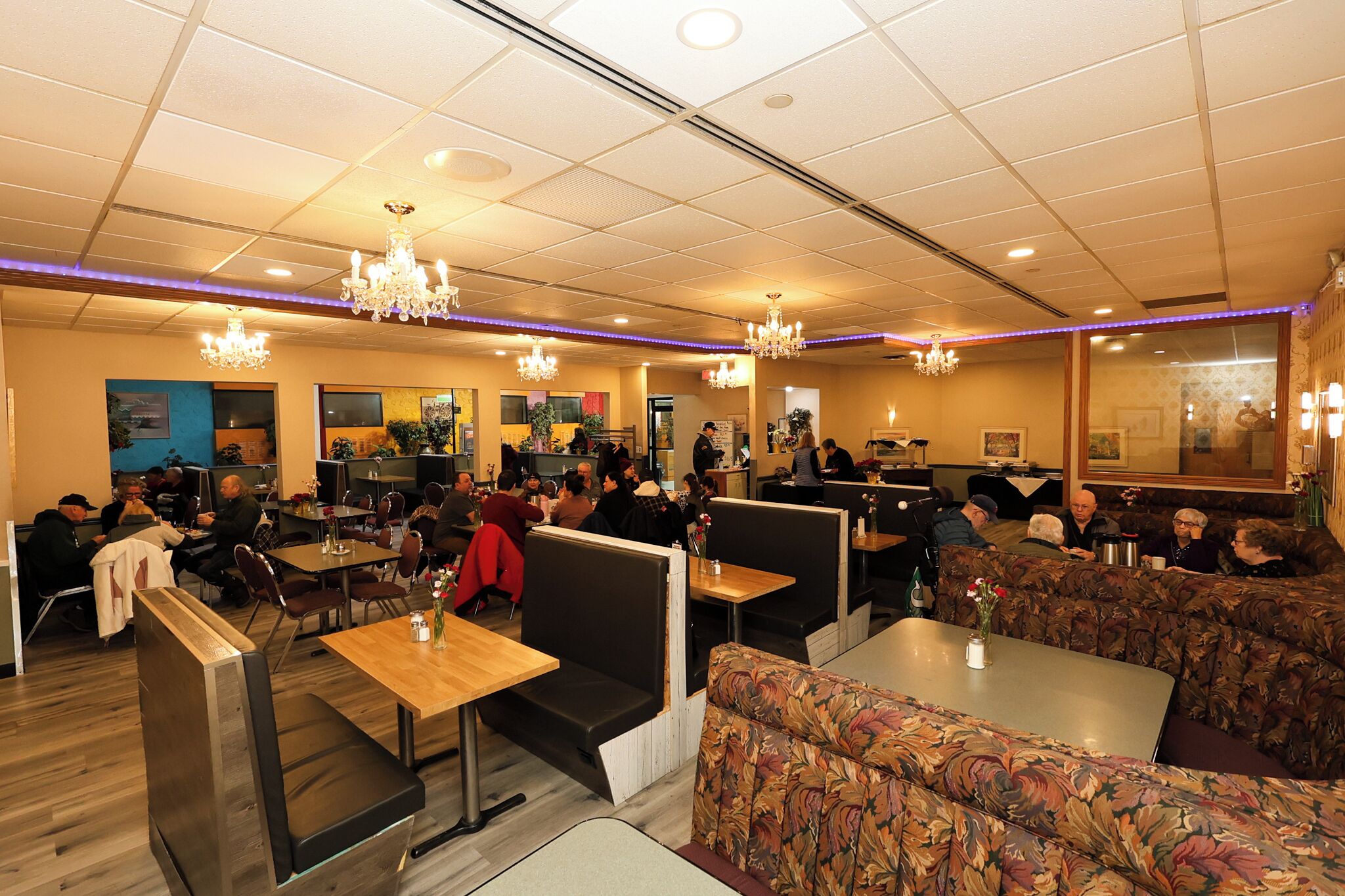 A restaurant with booths, tables, and chandeliers.