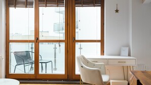 A modern room with a large sliding glass door, a white desk, a white chair, and a small table.