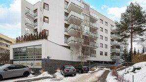 A multi-story building with balconies, a garage, and a snow-covered ground.