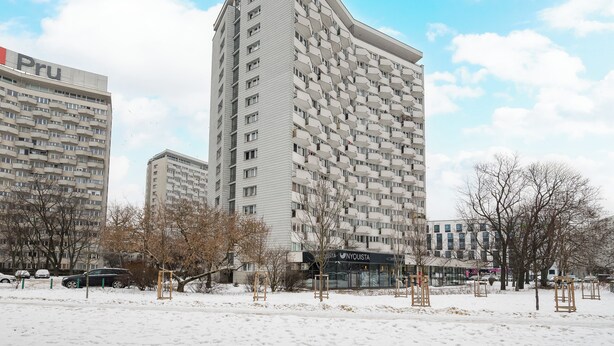 A modern high-rise building with a unique facade, surrounded by a snowy landscape and a few trees. - Solec Powiśle Harmony Apartment (Warszawa)