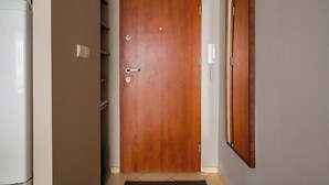 A wooden door with a handle and a keyhole, a white wall-mounted phone, and a tiled floor. - Solec Powiśle Harmony Apartment (Warszawa)
