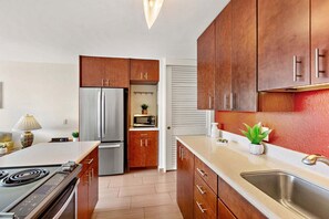 A modern kitchen with wooden cabinets, a stainless steel refrigerator, a microwave, and a sink. - New Listing! South Maui Condo Steps to Beach (Kihei)