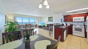 Un'ampia zona giorno con tavolo da pranzo, cucina e un balcone vista oceano.