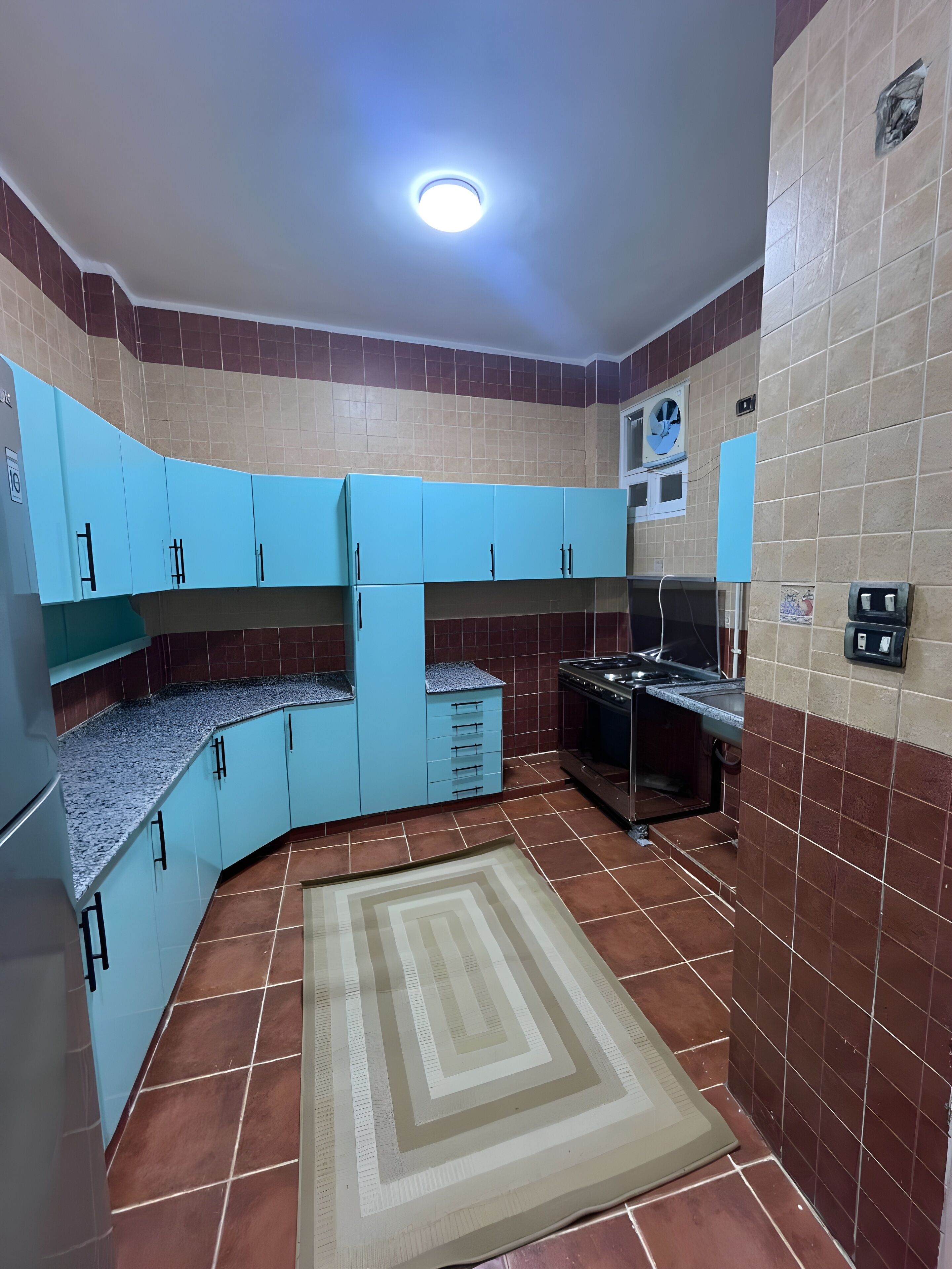 A kitchen with blue cabinets, a stove, and a tiled backsplash.