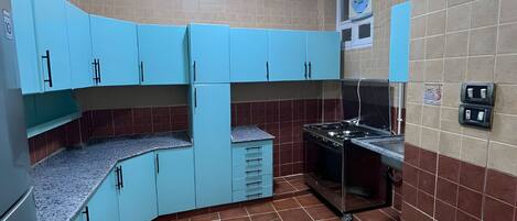 A kitchen with blue cabinets, a stove, and a tiled backsplash.