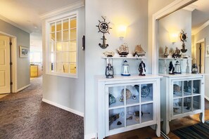 A hallway with a white console table displaying nautical-themed items.