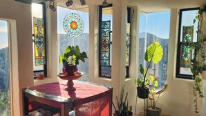 En spiseplads med et træbord og stole, omgivet af store vinduer med farvet glas.
