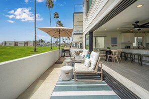 A balcony with outdoor seating, a grill, and a view of the beach. - Patio on the Boardwalk steps to the Ocean (Newport Beach)