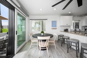 A modern kitchen with white cabinets, a granite countertop, and a built-in oven. - Patio on the Boardwalk steps to the Ocean (Newport Beach)