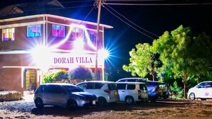 Un bâtiment appelé « DORAH VILLA », devant lequel sont garées plusieurs voitures.