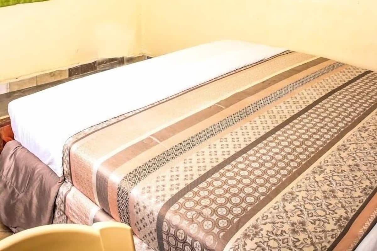 Ein Hotelzimmer mit einem Bett, einem Sessel, einem Fernseher und einem grünen Vorhang.