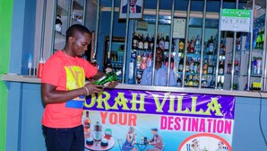 Un bar avec une enseigne indiquant « Paiement accepté par Mperesa » et une banderole sur laquelle on peut lire « Drah Villa, votre destination ».