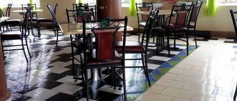 A dining area with checkered flooring, green curtains, and a central column.