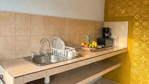 A kitchen with a sink, dish rack, coffee maker, and a fruit bowl on the counter. - Casitas Aramara | Sunset Loft in Lo de Marcos (Lo de Marcos)
