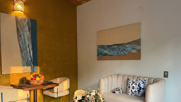 A living room with a sofa, coffee table, and a painting on the wall. - Casitas Aramara | Sunset Loft in Lo de Marcos (Lo de Marcos)