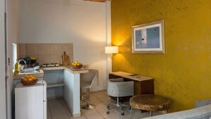A compact kitchen with a sink, a stove, and a countertop. There is a chair and a stool near the counter. - Casitas Aramara | Coastal Studio in Lo de Marcos (Lo de Marcos)