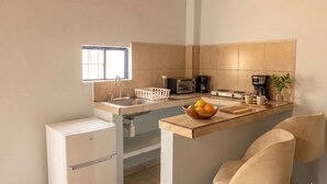 A compact kitchen with a built-in sink, a microwave, a coffee maker, and a small refrigerator. - Casitas Aramara | Coastal Studio in Lo de Marcos (Lo de Marcos)