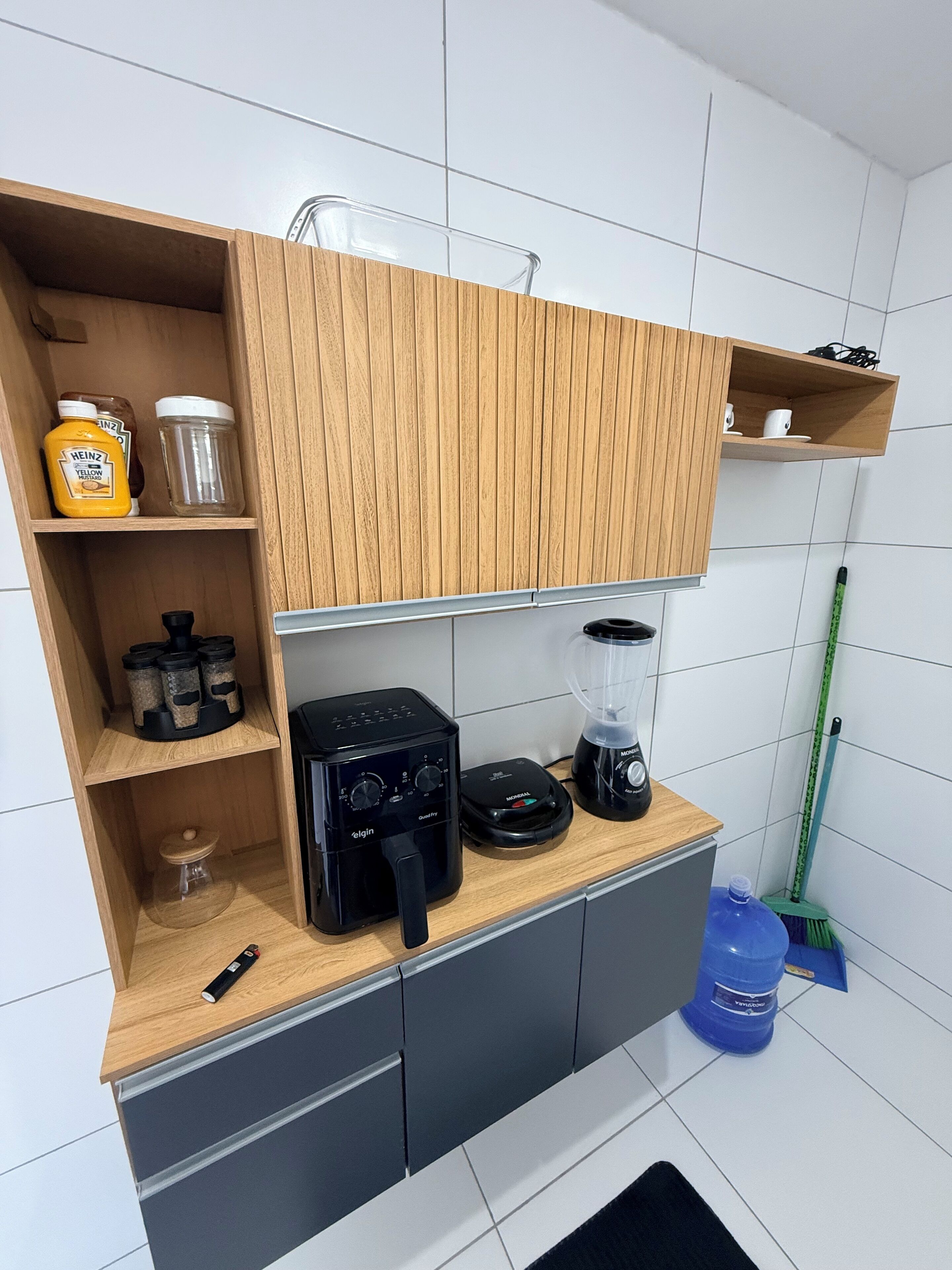 A kitchen with wooden cabinets, a coffee maker, a blender, and a mop.