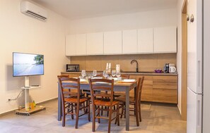 A compact kitchen with a dining area, a microwave, and a TV on a stand. - Lovely home in Santa Croce Camerina with house sea view (Santa Croce Camerina)