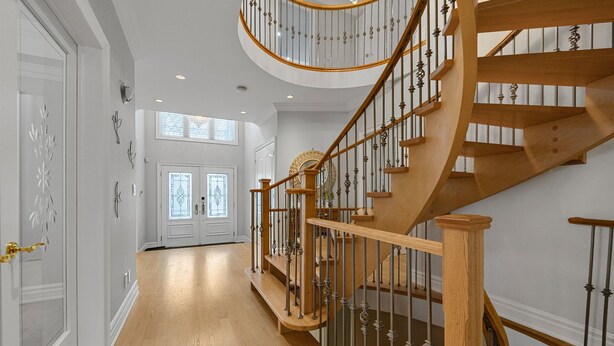 Un vaste hall d’entrée avec un escalier en bois orné de balustrades travaillées et surmonté d’un palier circulaire.