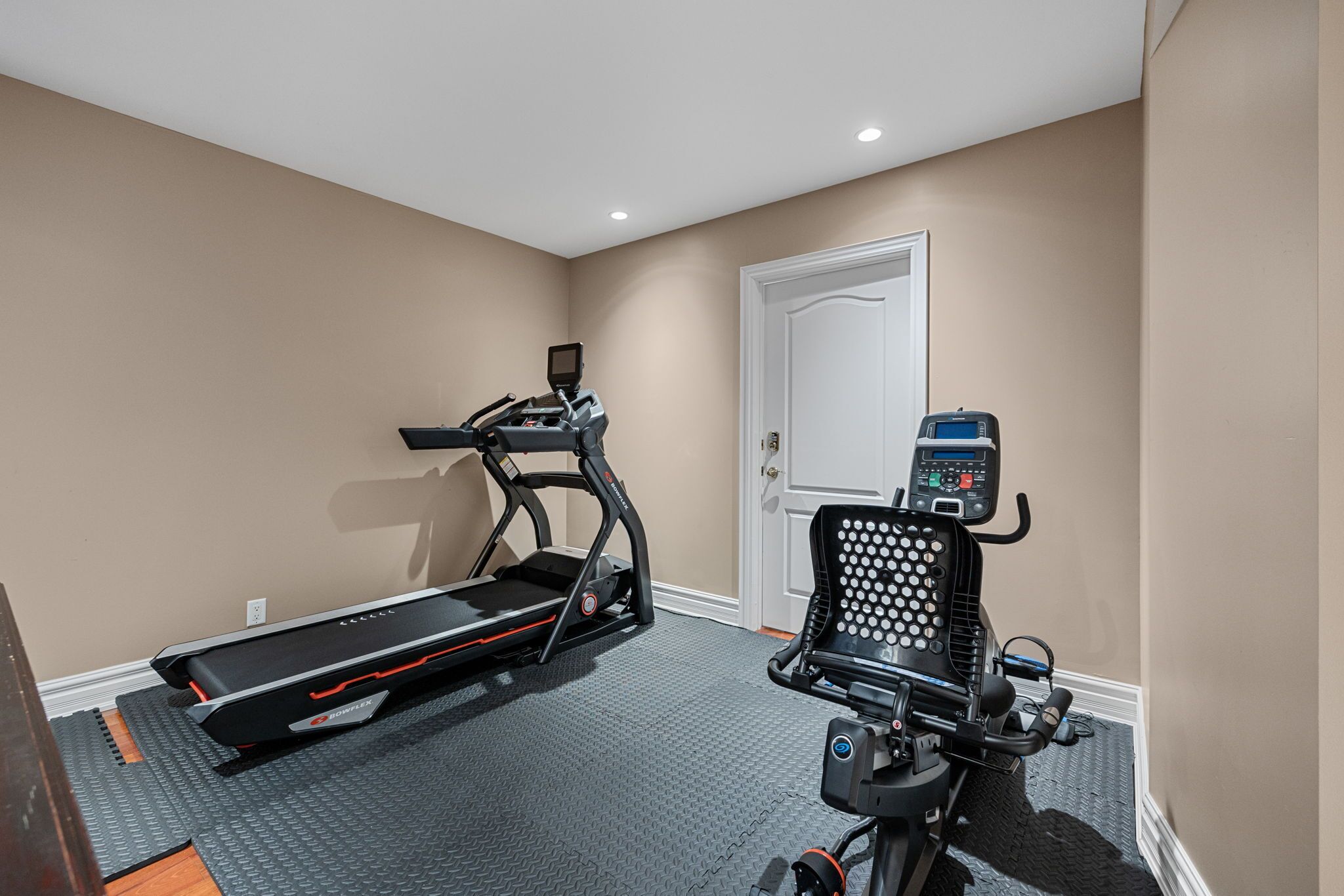 A home gym with a treadmill and an elliptical machine.