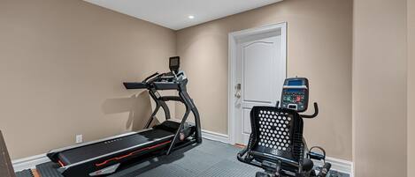 A home gym with a treadmill and an elliptical machine.