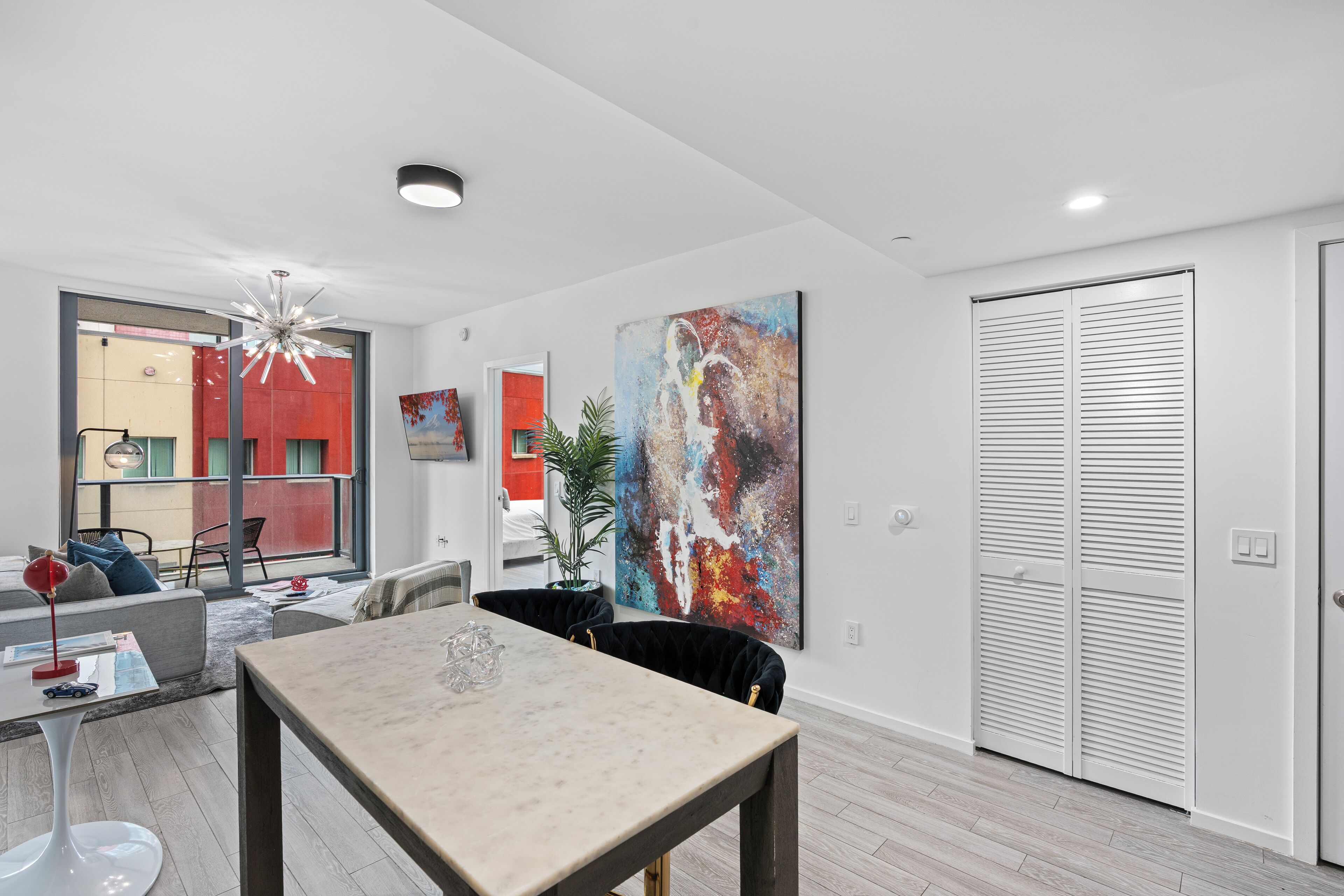 A modern living room with a dining table, a sofa, and a large window.