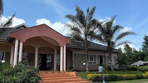 A two-story house with a red roof, a porch with columns, and a well-maintained garden with palm trees. - Alem Resort Tawa (Tawa)
