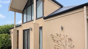 A modern two-story house with a flat roof, large windows, and a bench outside. - KozyGuru | Joslin | Private Self-Contained 1 BR (Joslin)