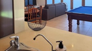 A modern living room with a pool table, a sofa, and a dining area with chairs and a TV. - KozyGuru | Joslin | Private Self-Contained 1 BR (Joslin)