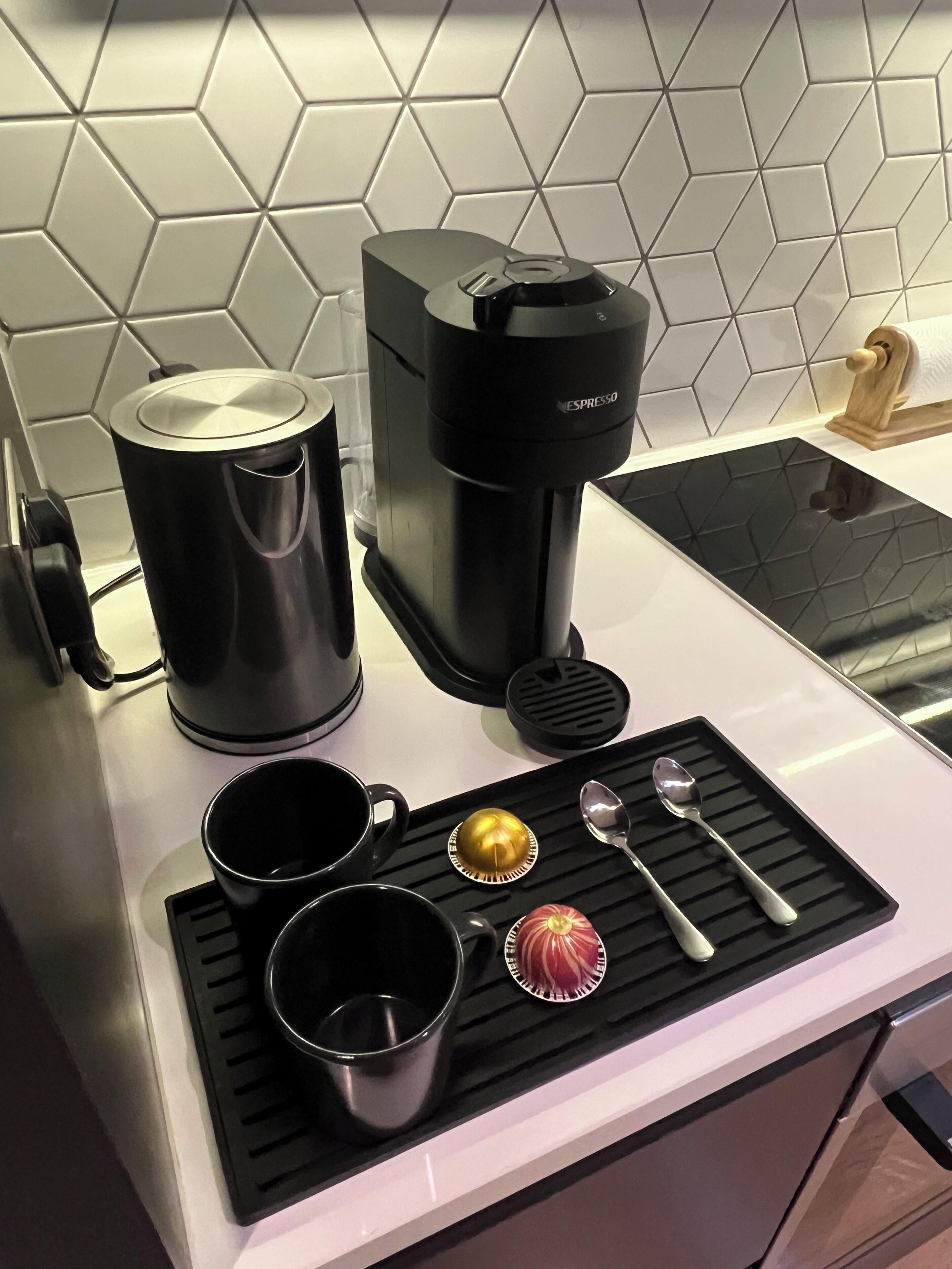 A kitchen counter with a coffee maker, a kettle, and two mugs.