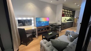 Ein modernes Wohnzimmer mit Flachbildfernseher, einer Couch, einem Couchtisch und einem Essbereich.
