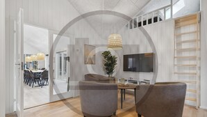 Ett modernt vardagsrum med en TV, två soffor, en matplats med stolar och ett stort fönster.