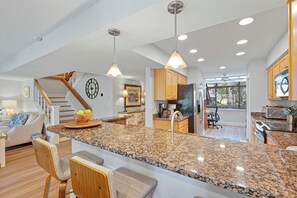 Eine geräumige Küche mit Granit Arbeitsplatten, Holzschränken und einer zentralen Kochinsel mit Barhockern.