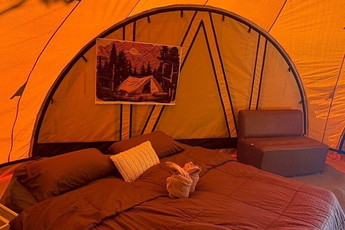 Une tente avec un lit, des oreillers et une couverture.