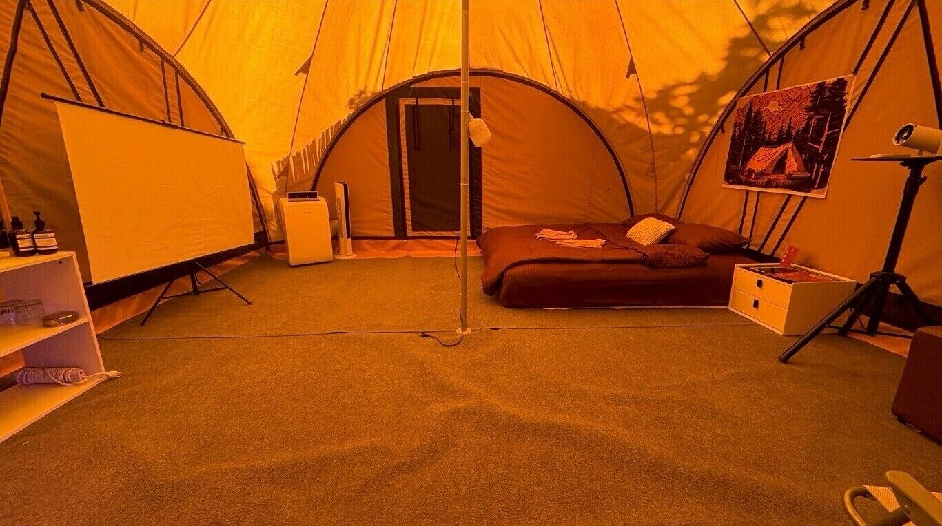 A tent with a bed, a desk, and a chair.