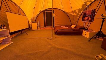 A tent with a bed, a desk, and a chair.