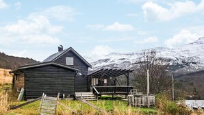 Eine rustikale Holzhütte mit geneigtem Dach, einer kleinen Veranda und einem Holzzaun.