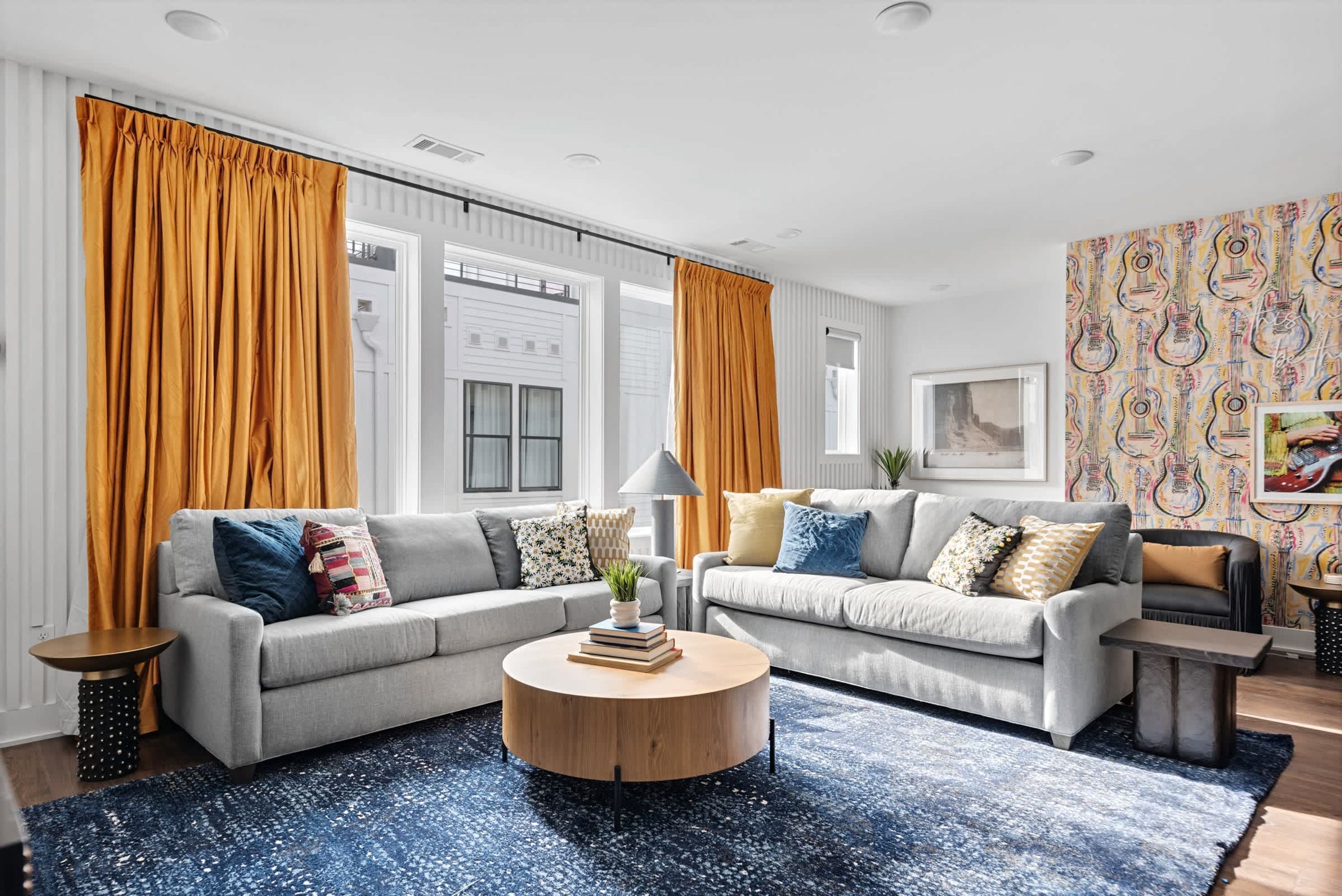 A modern living room with two grey sofas, a round wooden coffee table, and a patterned rug.