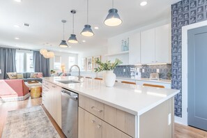 A modern kitchen with a central island, pendant lighting, and a backsplash with a geometric pattern. - Lucile 83 85 Double (Nashville)