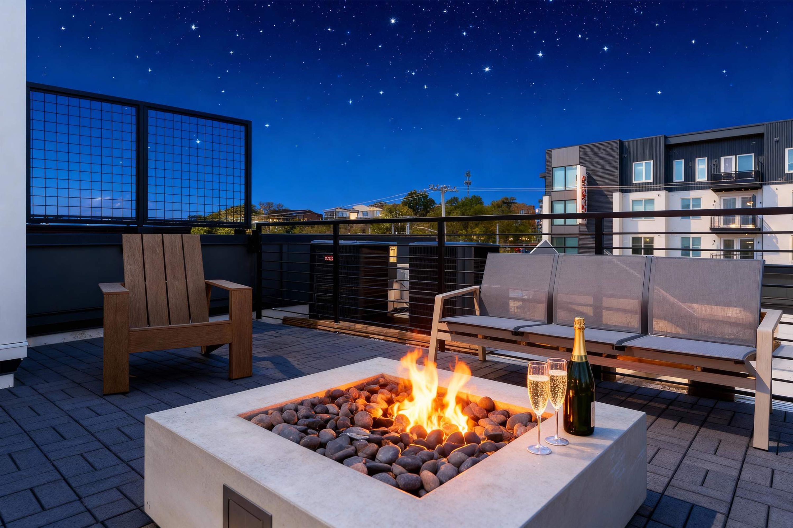 Eine Dachterrasse mit Feuerstelle, Sitzgelegenheiten im Freien und Blick auf den Nachthimmel.